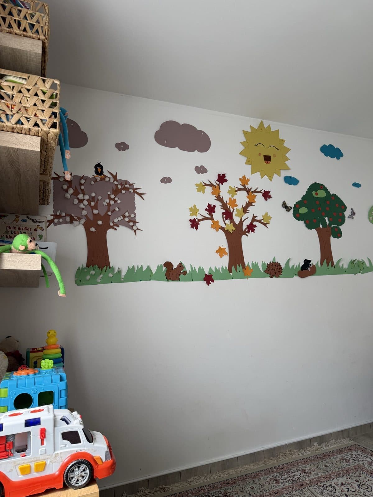 Selbst gebastelte Jahreszeiten-Wand mit Bäumen, Sonne und Tieren aus Papier