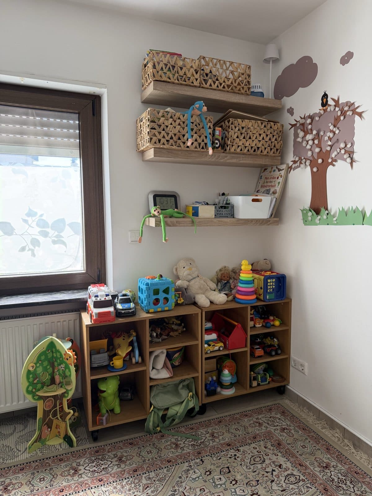 Das Spielzimmer mit Holzregalen, Körben, Bilderbüchern und selbst gebastelter Wanddekoration